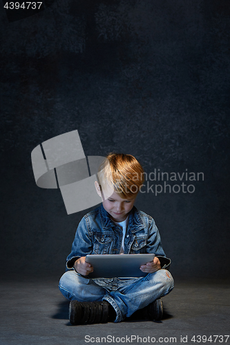 Image of Little boy sitting with tablet in studio