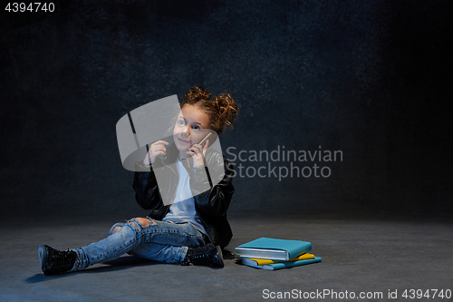 Image of Little girl sitting with smartphone in studio