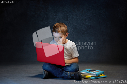 Image of Little boy sitting with laptop in studio