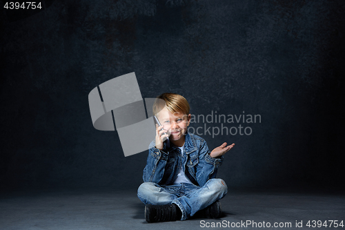 Image of Little boy sitting with smartphone in studio