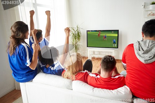 Image of football fans watching soccer game on tv at home