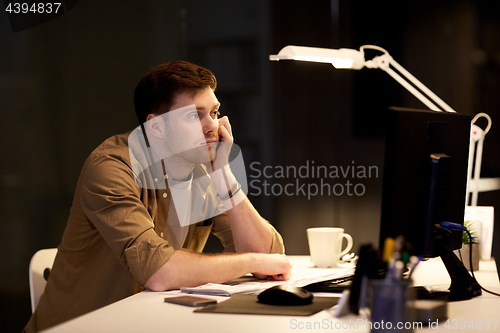 Image of tired or bored man on table at night office