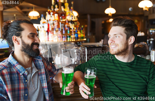 Image of male friends drinking green beer at bar or pub