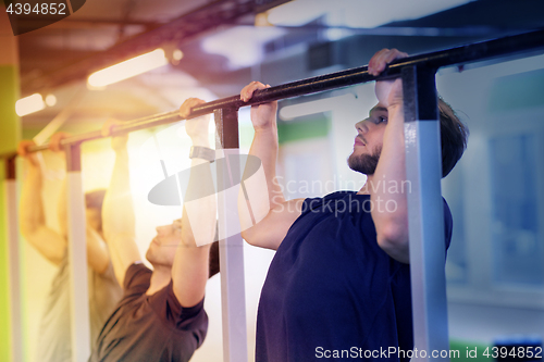 Image of group of young men doing pull-ups in gym