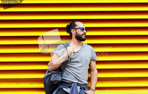 Image of man in sunglasses with bag standing at street wall