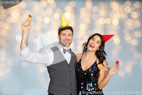 Image of happy couple with party blowers having fun