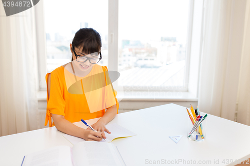 Image of happy student girl with book and notebook at home