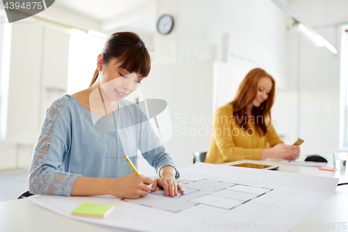 Image of female architect with blueprint working at office