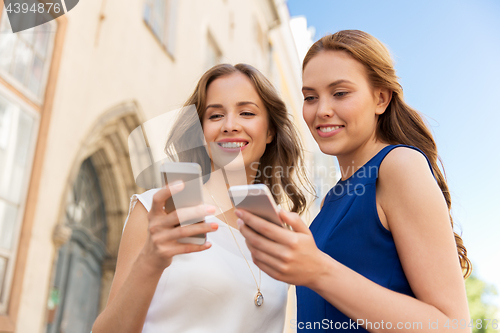 Image of happy women with smartphones on city street