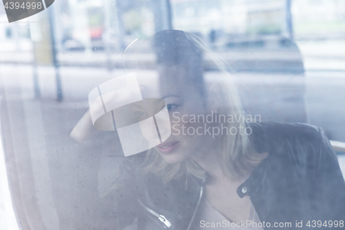 Image of Young woman traveling by train, looking out window while sitting in train.