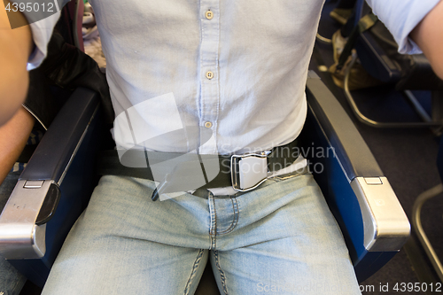 Image of Male passenger with seat belt fastened while sitting on airplane for safe flight.