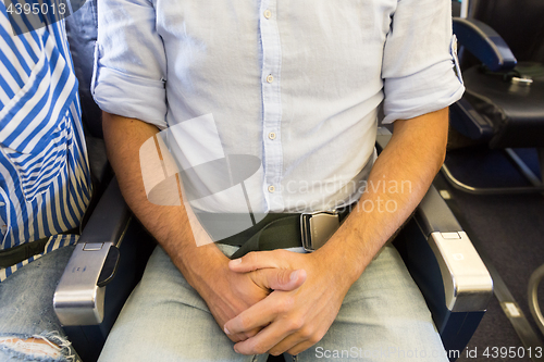 Image of Male passenger with seat belt fastedned while sitting on airplane for safe flight.