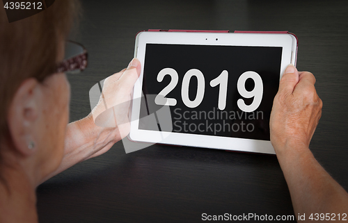 Image of Senior lady relaxing and her tablet - 2019