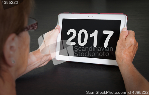 Image of Senior lady relaxing and her tablet - 2017