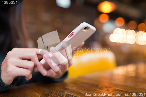 Image of Woman texting on mobile phone in coffee shop