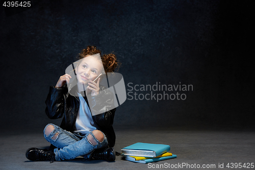 Image of Little girl sitting with smartphone in studio