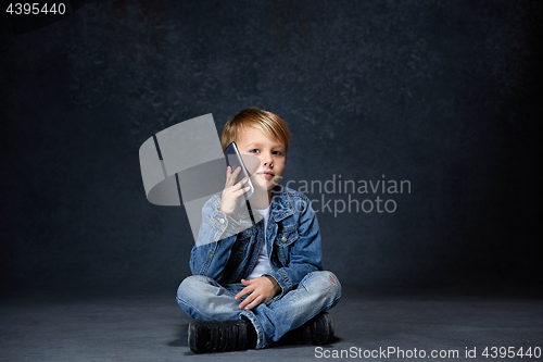 Image of Little boy sitting with smartphone in studio