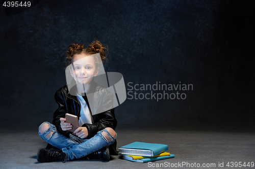 Image of Little girl sitting with smartphone in studio
