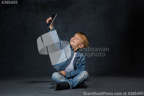 Image of Little boy sitting with smartphone in studio