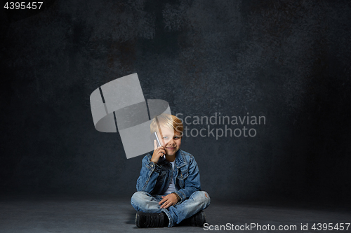 Image of Little boy sitting with smartphone in studio