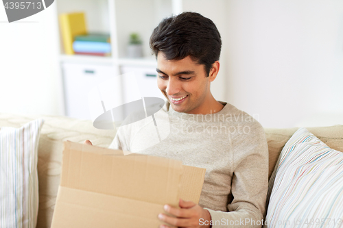 Image of happy man opening parcel box at home