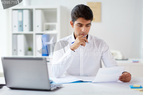 Image of businessman working with papers at office