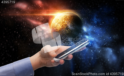 Image of hand holding smartphone over planet in space