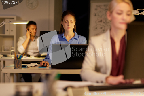 Image of businesswoman at computer working at night office