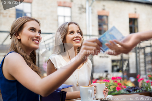 Image of young women paying for coffee at street cafe