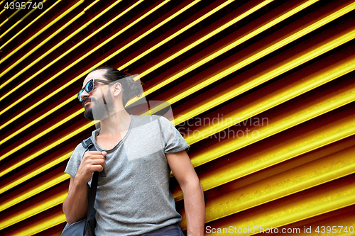 Image of man in sunglasses with bag standing at street wall