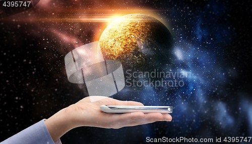 Image of hand holding smartphone over planet in space