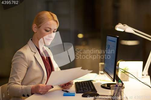 Image of businesswoman with papers working at night office