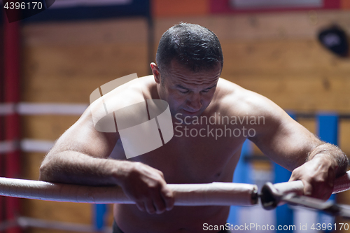 Image of kick boxer resting on the ropes in the corner