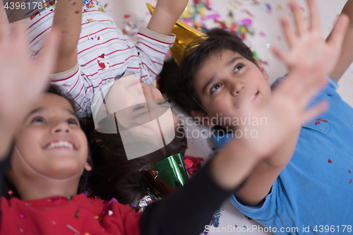 Image of kids  blowing confetti while lying on the floor