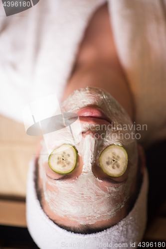 Image of woman is getting facial clay mask at spa