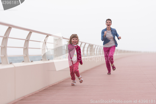 Image of mother and cute little girl on the promenade by the sea