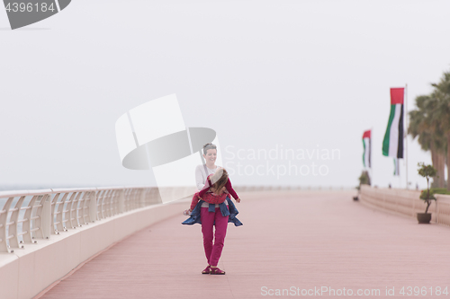 Image of mother and cute little girl on the promenade by the sea