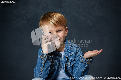 Image of Little boy sitting with smartphone in studio