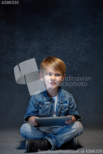 Image of Little boy sitting with tablet in studio