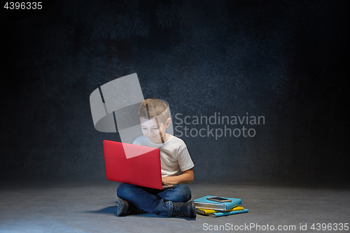 Image of Little boy sitting with laptop in studio