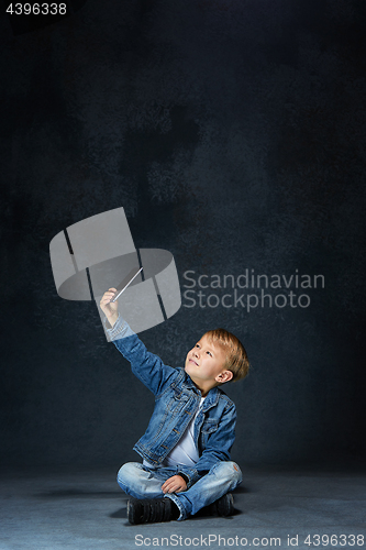 Image of Little boy sitting with smartphone in studio