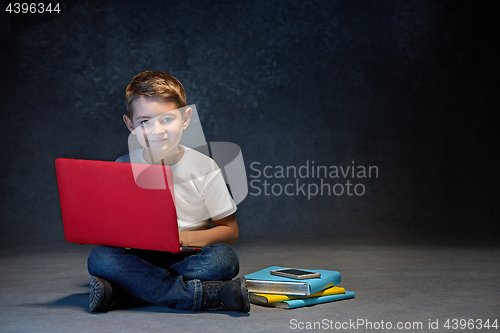 Image of Little boy sitting with laptop in studio