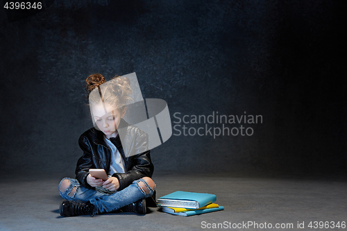 Image of Little girl sitting with smartphone in studio