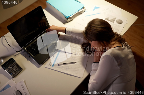 Image of tired woman sleeping on office table at night