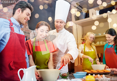 Image of happy friends and chef cook baking in kitchen