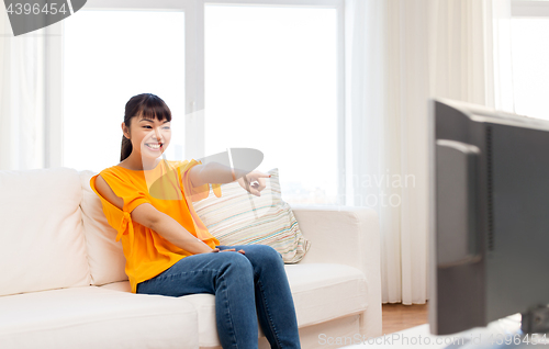 Image of happy asian woman with watching tv at home