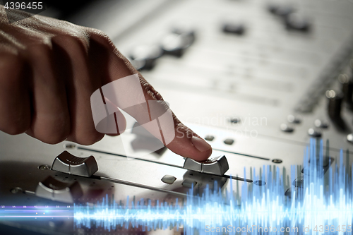 Image of hand using mixing console for music recording