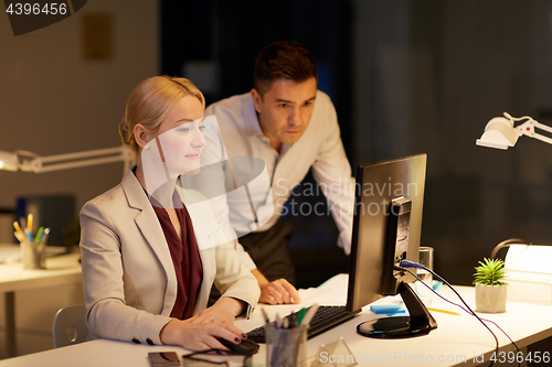Image of business team with computer working late at office