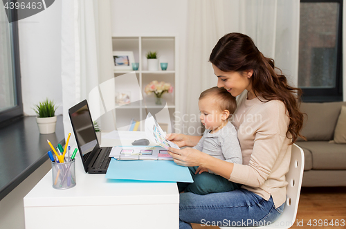 Image of mother with baby and documents working at home