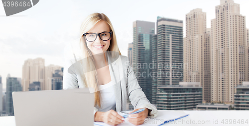 Image of businesswoman with notepad and laptop at office